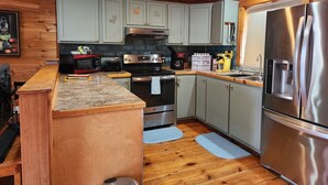 A kitchen with wooden cabinets, stainless steel appliances, and a granite countertop. - Beautiful and modern cape style cottage nested along the Jordan Tidal River. (Lamoine)