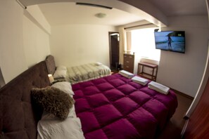 A bedroom with a bed, a dresser, and a television on the wall. - Inkaclub Miraflores (Lima)