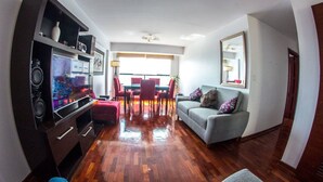 A living room with a TV, a sofa, a dining table with chairs, and a kitchen area with cabinets and appliances. - Inkaclub Miraflores (Lima)