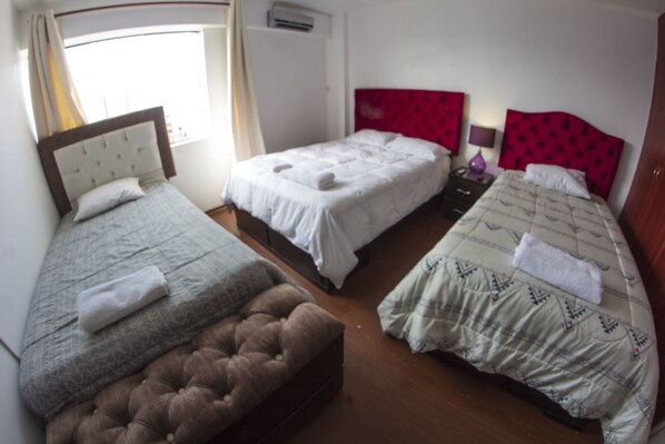A hotel room with three beds, a brown ottoman, and a window with curtains. - Inkaclub Miraflores (Lima)