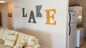 A living room with a striped sofa, a refrigerator, and decorative letters spelling "LAKE" on the wall. - Lake front cottage with dock (Lexington)