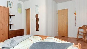 A room with a bed, wooden wardrobe, and a chair.