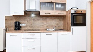 A modern kitchen with white cabinets, a wooden countertop, a stove, and a coffee maker.