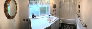 Een badkamer met een witte wastafel, een spiegel, een toilet en een bad.
