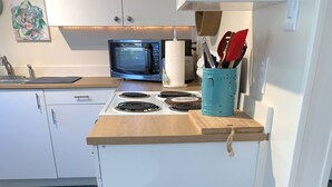 A kitchen with a microwave, stove, and trash bins.