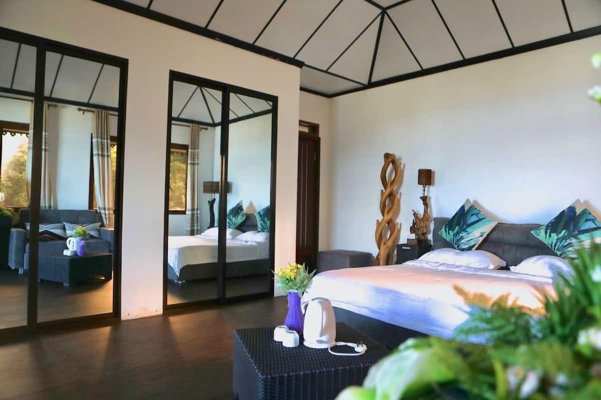 A modern bedroom with a large bed, a mirror, and a seating area with a sofa and coffee table.