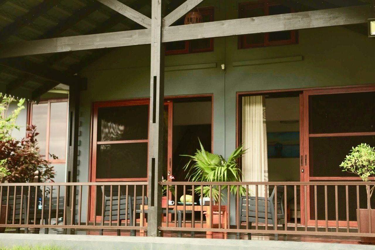 A building with a covered porch, large windows, and a railing.