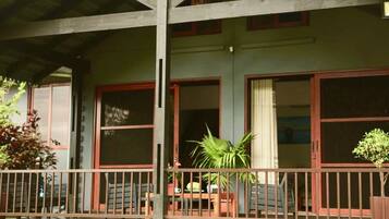 A building with a covered porch, large windows, and a railing.
