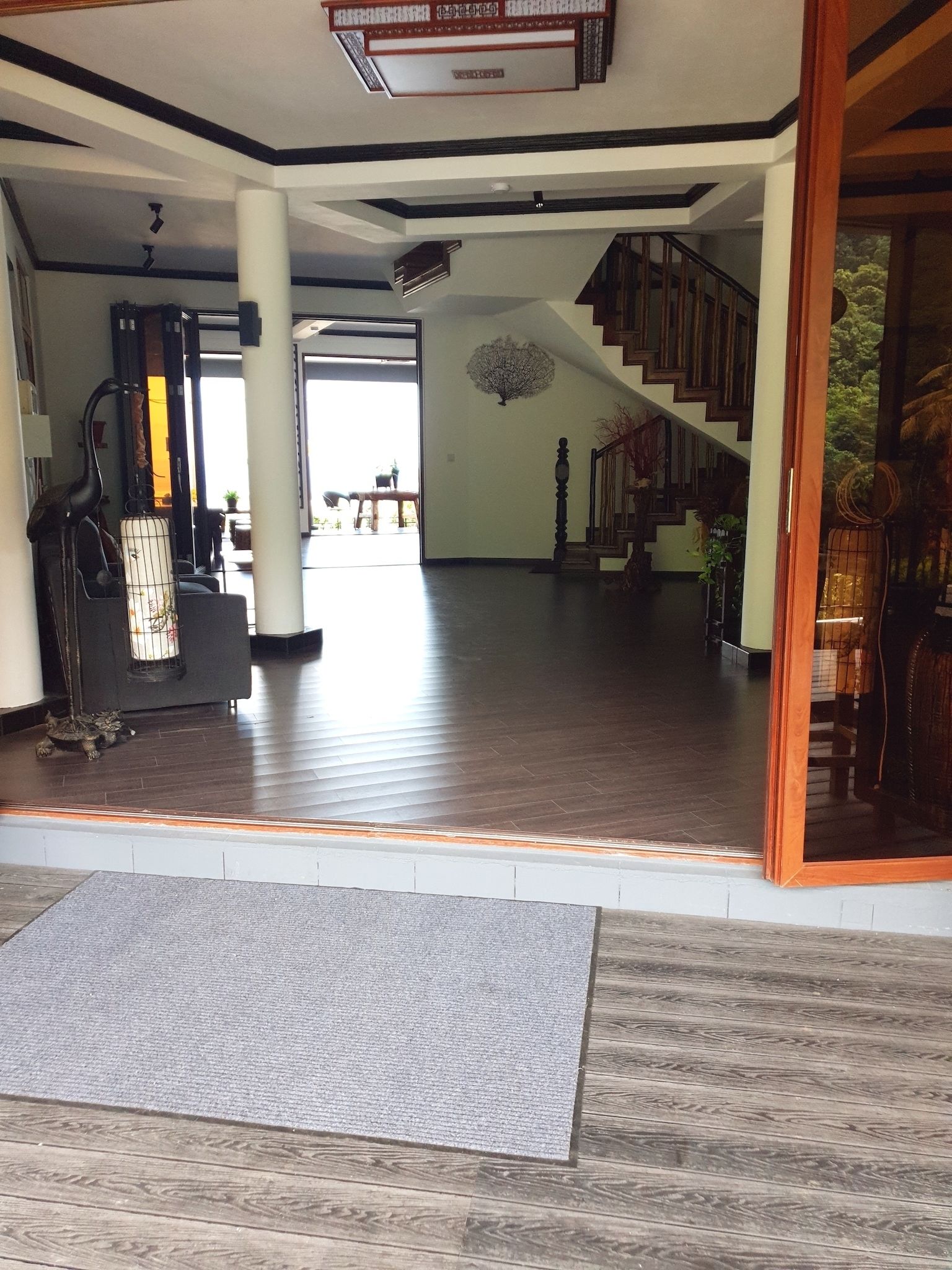 A spacious interior with a wooden floor, a staircase leading to an upper level, and a view of the outdoors.