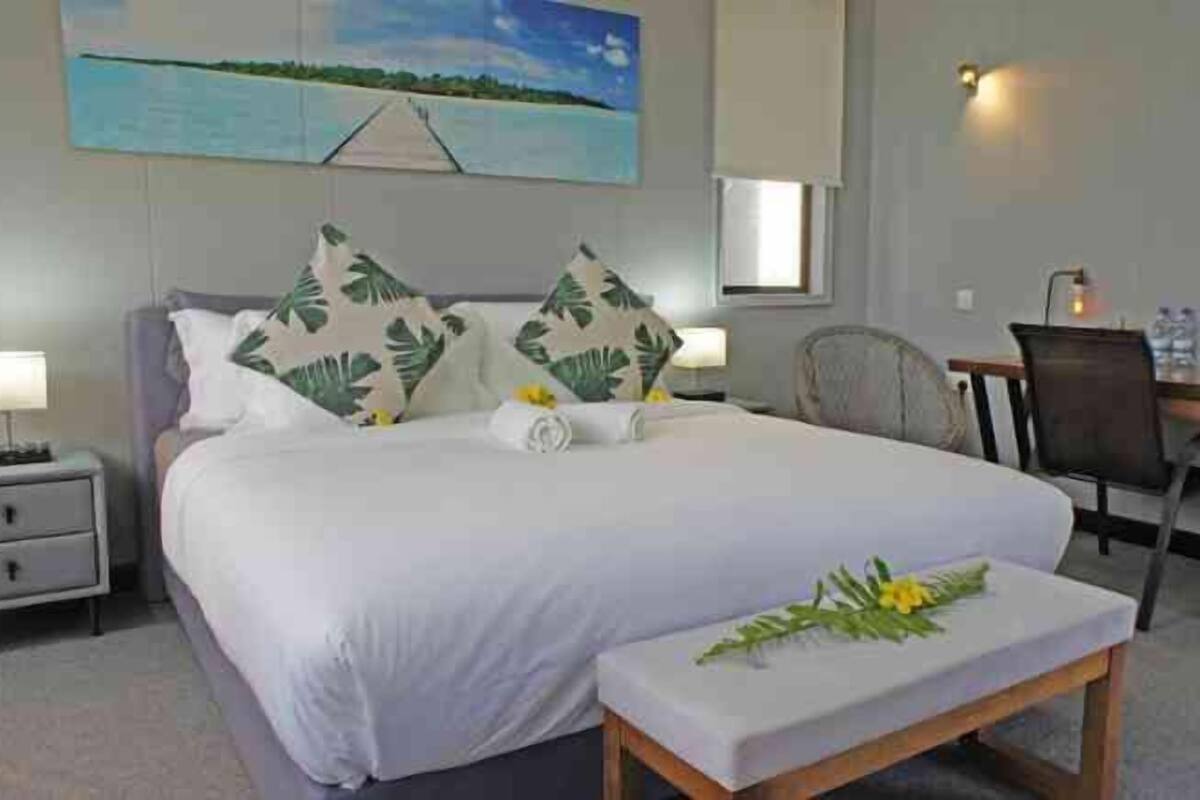 A hotel room with a large bed, two nightstands, a desk, and a chair.