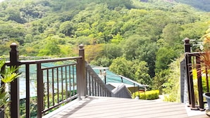 A wooden staircase leading to a balcony overlooking a lush green valley with a mountain in the background. - Blue Hill (Mahé Island)
