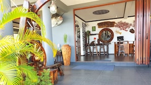 A reception area with a wooden desk, chairs, and a large potted plant. - Blue Hill (Mahé Island)
