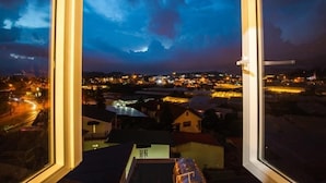 A view from a window overlooking a cityscape at night with illuminated buildings and a cloudy sky. - Huong Anh Luxury Hotel Dalat (Lang Biang - Da Lat)