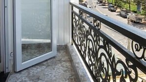 A balcony with a glass door, a metal railing, and a view of a street with cars and trees. - Huong Anh Luxury Hotel Dalat (Lang Biang - Da Lat)