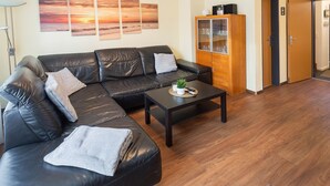 Una sala de estar con un sofá de cuero negro, una mesa de centro y un aparador con puertas de vidrio.