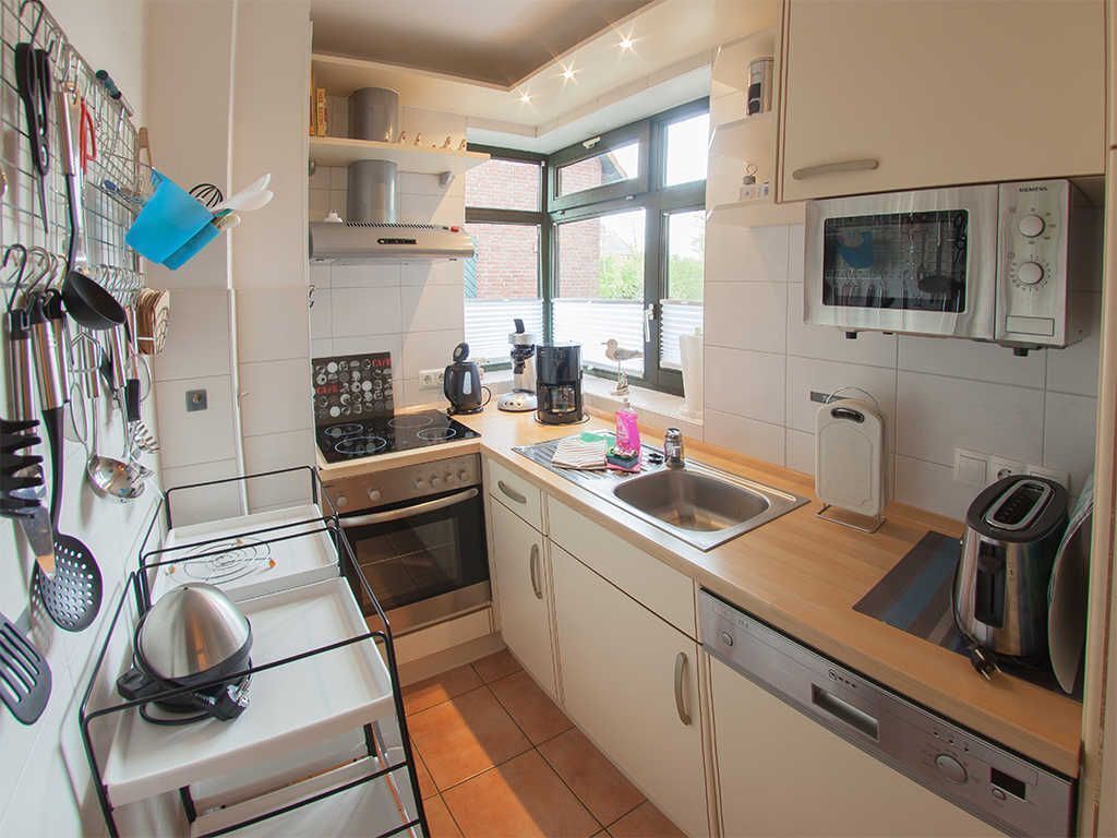 A compact kitchen with white cabinets, a microwave, a coffee maker, and a stove.