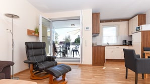 A modern living area with a leather recliner, a dining table, and a kitchen with wooden cabinets. - House Pier 18 - Holiday apartment 9 (Esens)