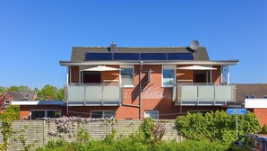 A two-story residential building with a balcony, a satellite dish, and a blue sign in front. - House Pier 18 - Holiday apartment 9 (Esens)