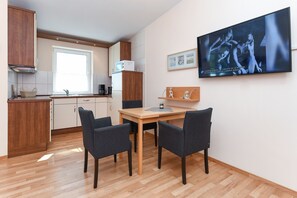 Cozinha moderna com armários de madeira, micro-ondas e sala de jantar com mesa e cadeiras.