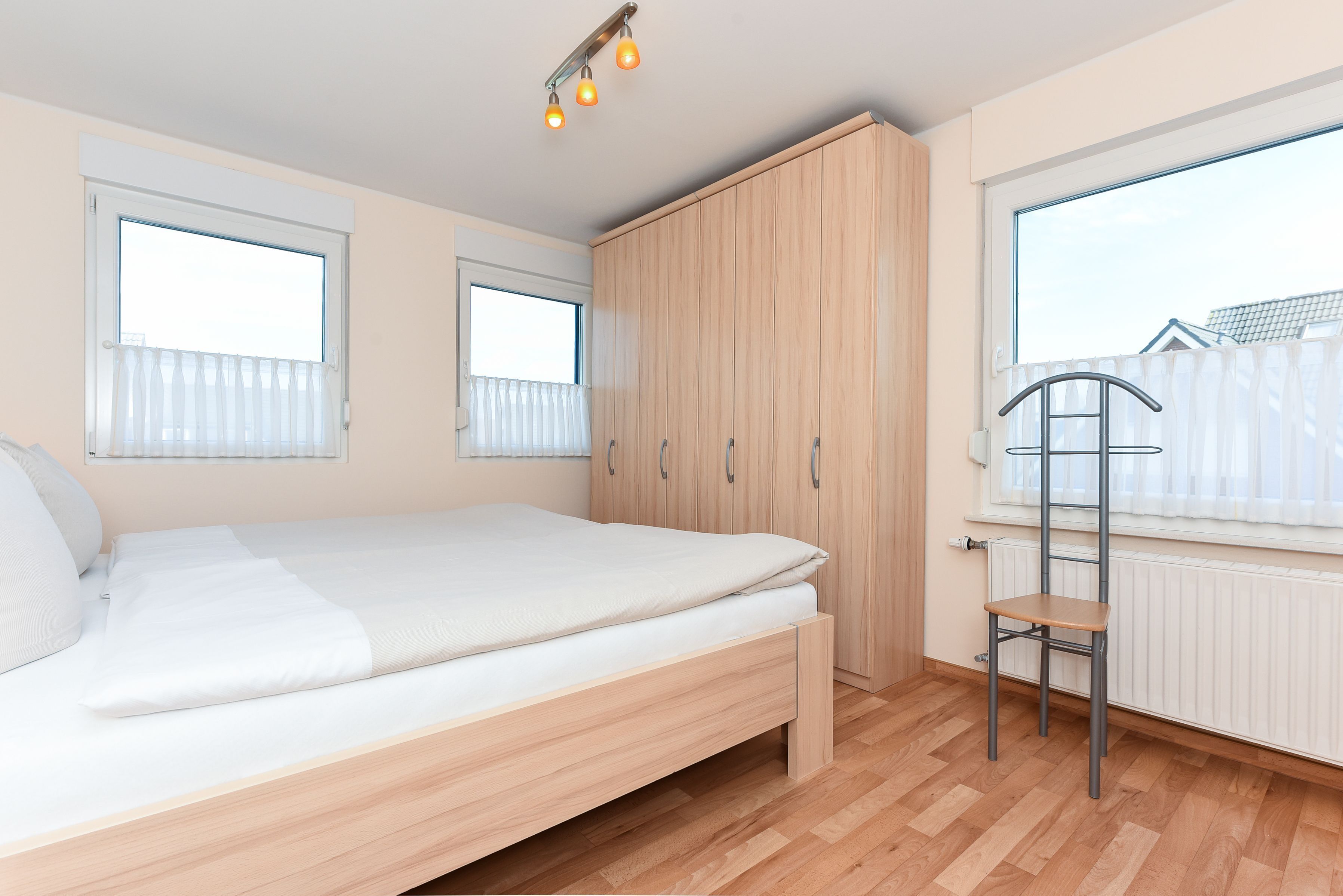Habitació amb llit, armari, finestra i radiador.