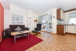 Uma sala de estar moderna com um sofá, uma mesa de centro, um tapete vermelho e uma cadeira preta.