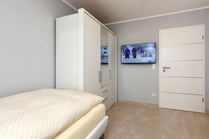 Une chambre à coucher avec un lit, une armoire et un téléviseur fixé au mur.