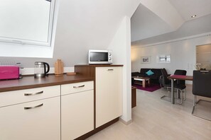 Une cuisine moderne équipée d’un four à micro-ondes, d’une machine à café et d’une valise rose.