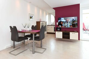 Une cuisine moderne avec un coin repas, un téléviseur et un mur d’accent rouge.