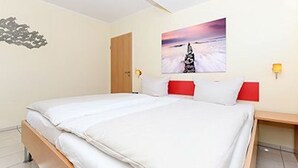 Une chambre d’hôtel avec un lit, un tableau au mur et un oreiller rouge.
