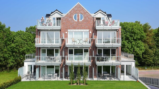 Un immeuble à plusieurs étages, doté d’une façade en briques, de grandes fenêtres et de balcons.