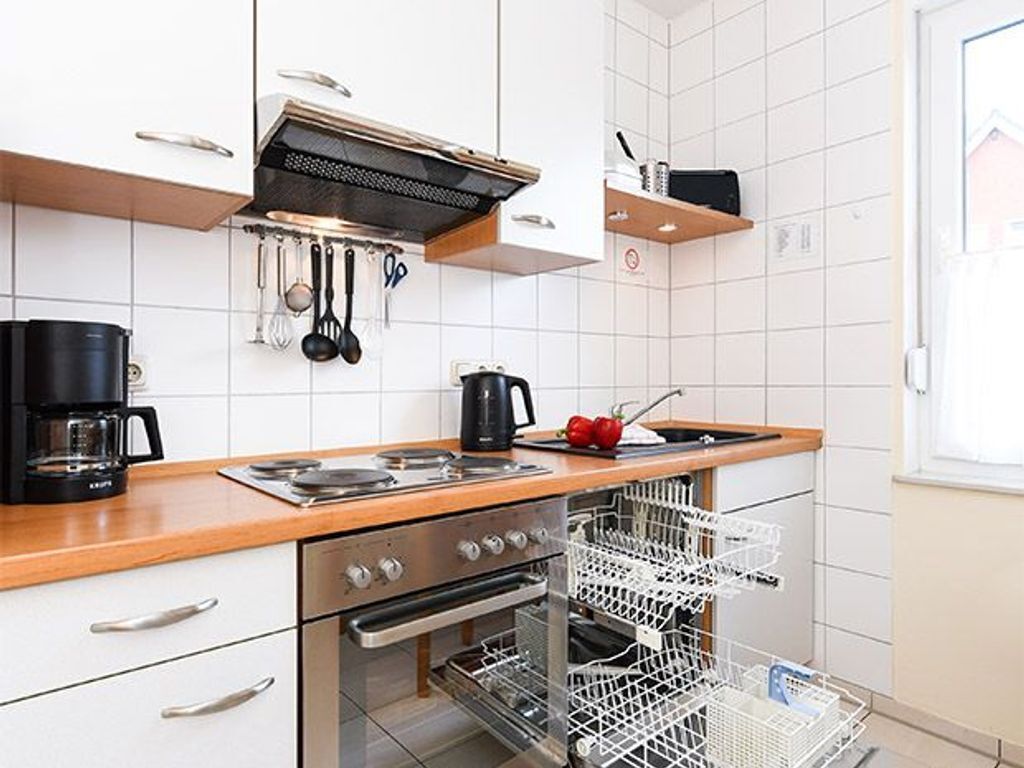 Eine moderne Küche mit weißen Schränken, Edelstahlgeräten und einem Geschirrspüler.