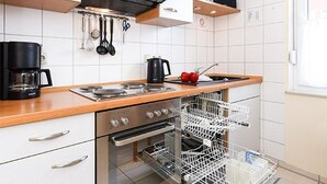 Ett modernt kök med vita skåp, vitvaror i rostfritt stål och en diskmaskin.