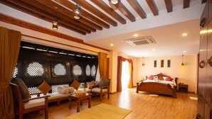 Una habitación amplia con suelo de madera, cama con ropa de cama roja, un conjunto de sofá y una pequeña mesa.