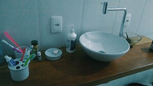 A bathroom sink with a large bowl, a faucet, and a soap dispenser. There are toothbrushes in a holder and a bottle of hand soap on the counter.