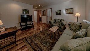Una sala de estar con televisor, sofá, sillón, mesa de centro y alfombra.