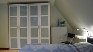 A bedroom with a bed, a wardrobe, a desk with a chair, and a lamp. - FeWo-Schuberski (Oerlinghausen)