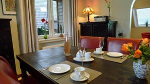 A dining area with a table set for two, a lamp, a radio, and a vase with flowers. - FeWo-Schuberski (Oerlinghausen)