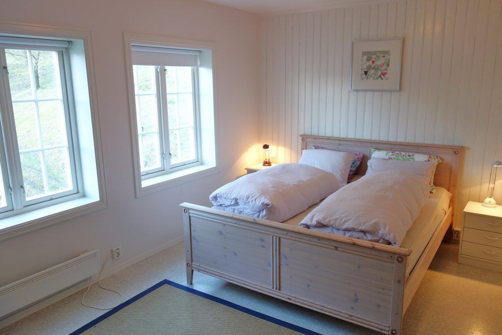 A bedroom with a wooden bed, two bedside tables, a nightstand, and a window.