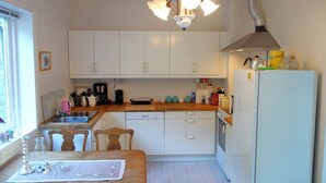 Una cocina compacta con armarios blancos, encimera de madera, horno integrado y extractor de acero inoxidable.