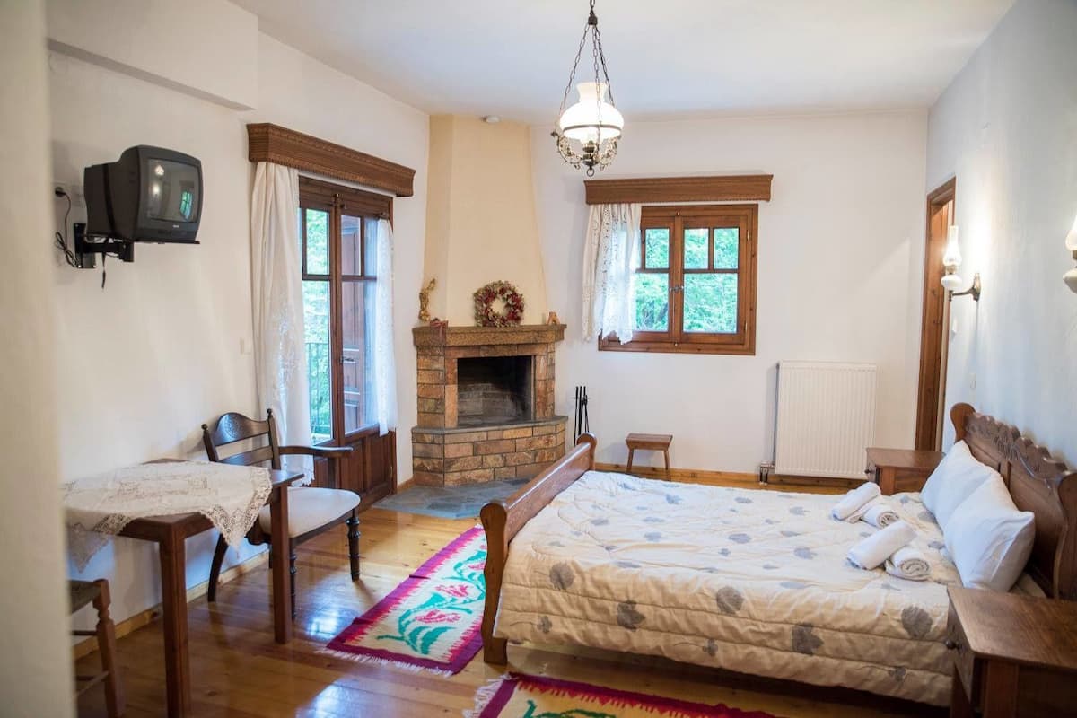 Un dormitorio con chimenea, cama, escritorio y televisor.