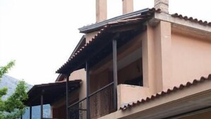Un edificio de dos pisos con un balcón, una escalera y una pila de leña.