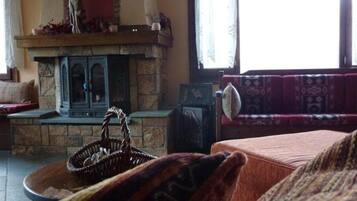 A cozy living room with a stone fireplace, a sofa, and a table with a basket.