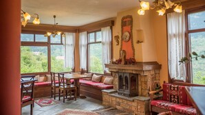 Una habitación acogedora con chimenea, asientos y grandes ventanales con vistas al exterior.