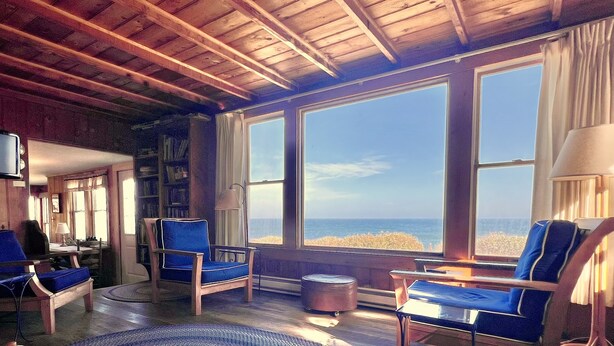 A cozy room with large windows, a wooden ceiling, and a blue rug. - Nauset Heights - The Ocean At Your Doorstep! (2127) (Orleans)