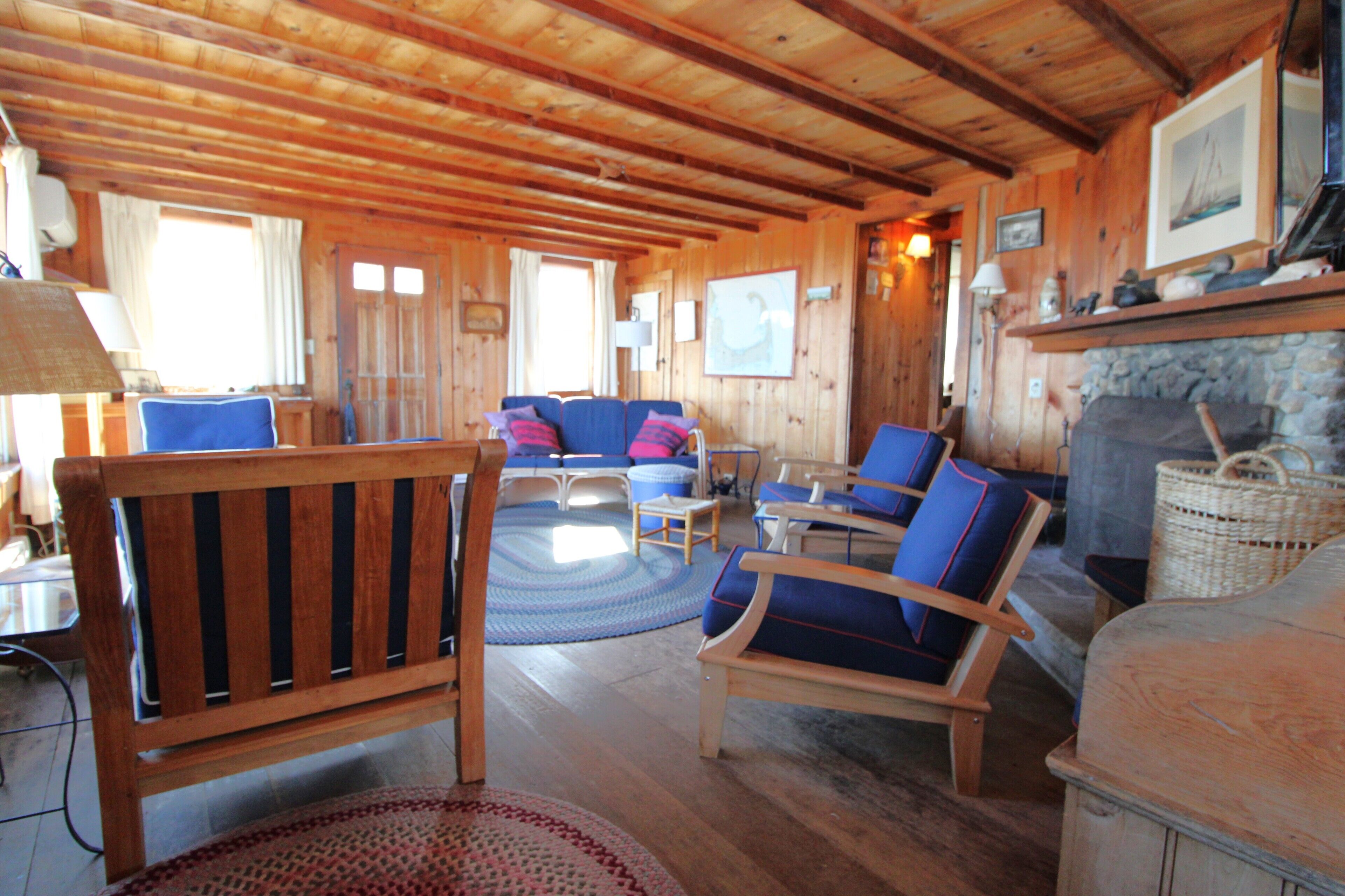 L’intérieur d’un chalet en bois comprend un espace de vie avec un canapé, des fauteuils et une cheminée.