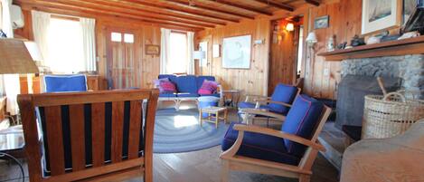 L’intérieur d’un chalet en bois comprend un espace de vie avec un canapé, des fauteuils et une cheminée.