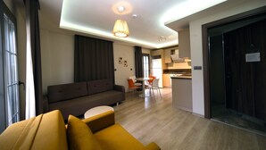 A modern living room with a sofa, a dining table with chairs, and a kitchen area in the background.