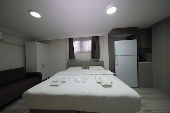 Una habitación de hotel con una cama, un sofá, un minibar y un refrigerador.