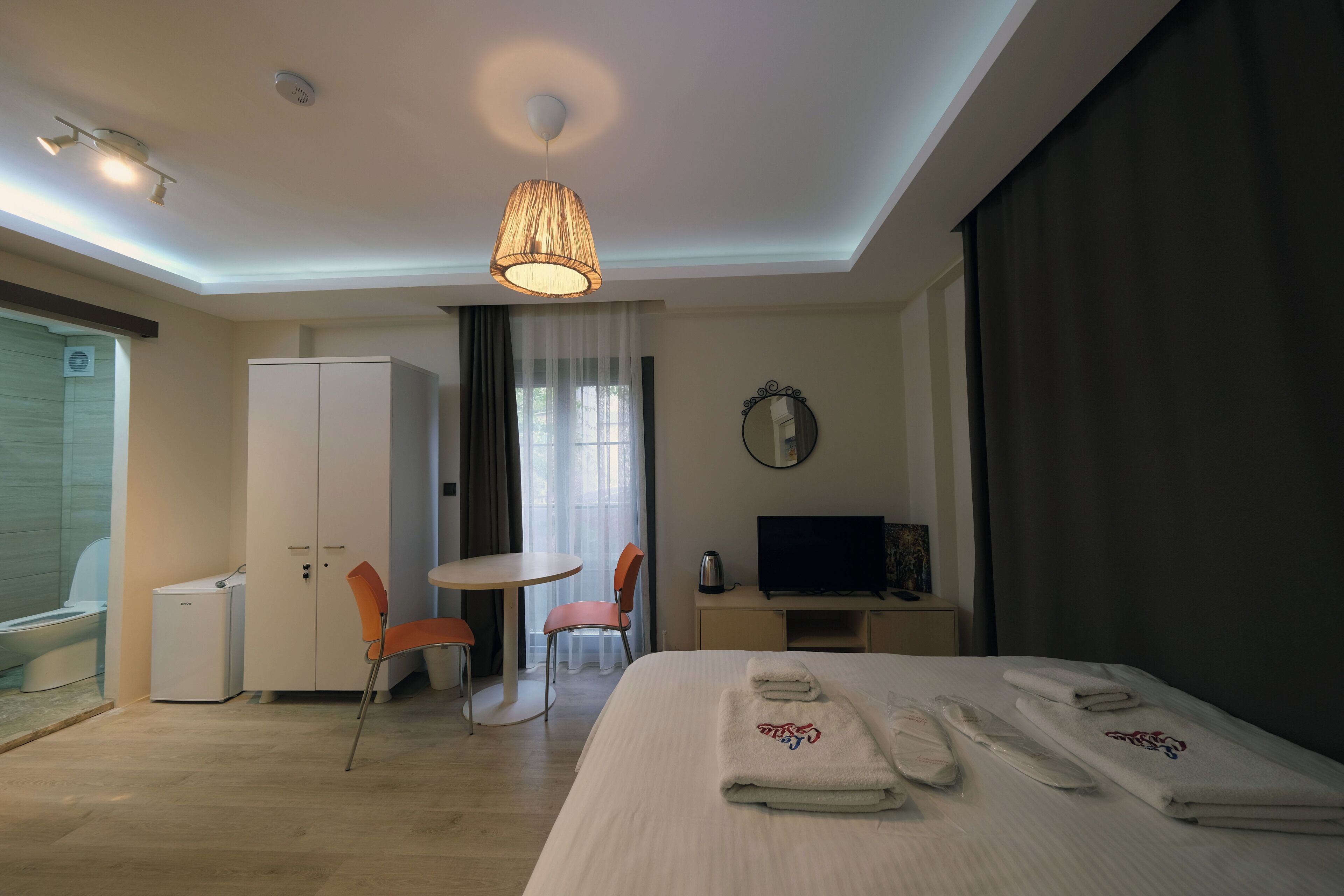 A hotel room with a bed, a desk, a chair, a television, and a bathroom.
