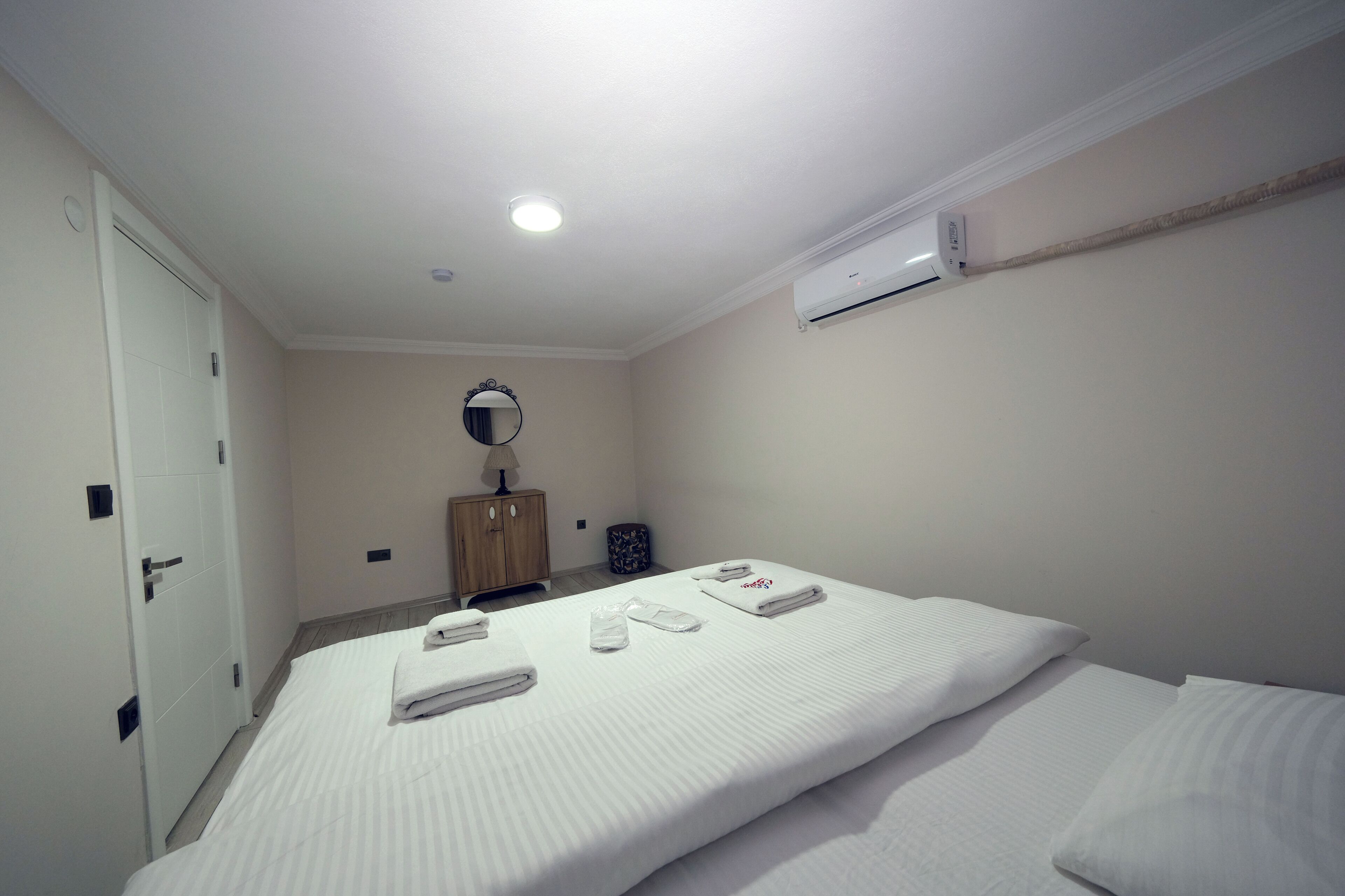 A hotel room with two beds, a wardrobe, a mirror, and an air conditioning unit.